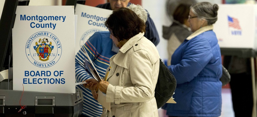 People cast their vote in the scanner machine at polling place during the U.S. midterm election Tuesday, Nov. 6, 2018, in Silver Spring, Md. 